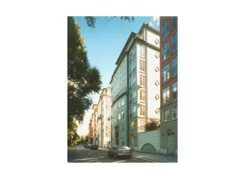 A carefully detailed row of apartments frame one side of the public space of the street (with rows of trees in a park framing the other side) at Sankt Erik, a Charter-Award-winning development on the grounds of a closed medical institution in Stockholm.