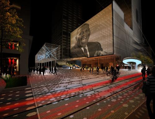 A rendering of the main plaza in the Main Street Arts District, showing a projection of Howlin' Wolf on a modern building, cyclists, streetcar lines, and permeable pavers.